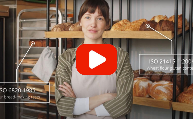 thumbnail of video showing person in bakery folding arms standards and play icon on image