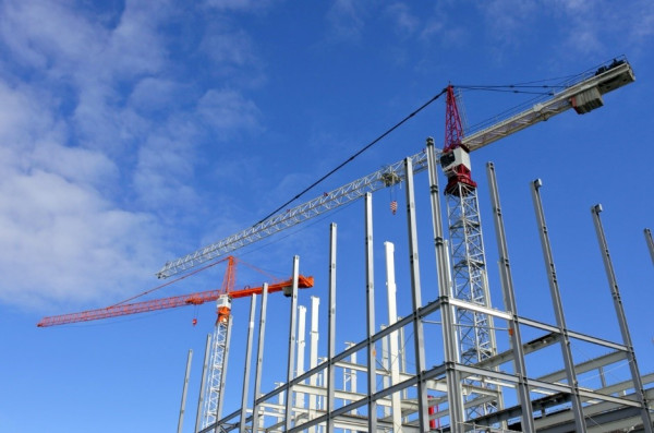 Cranes over a steel structure under construction.